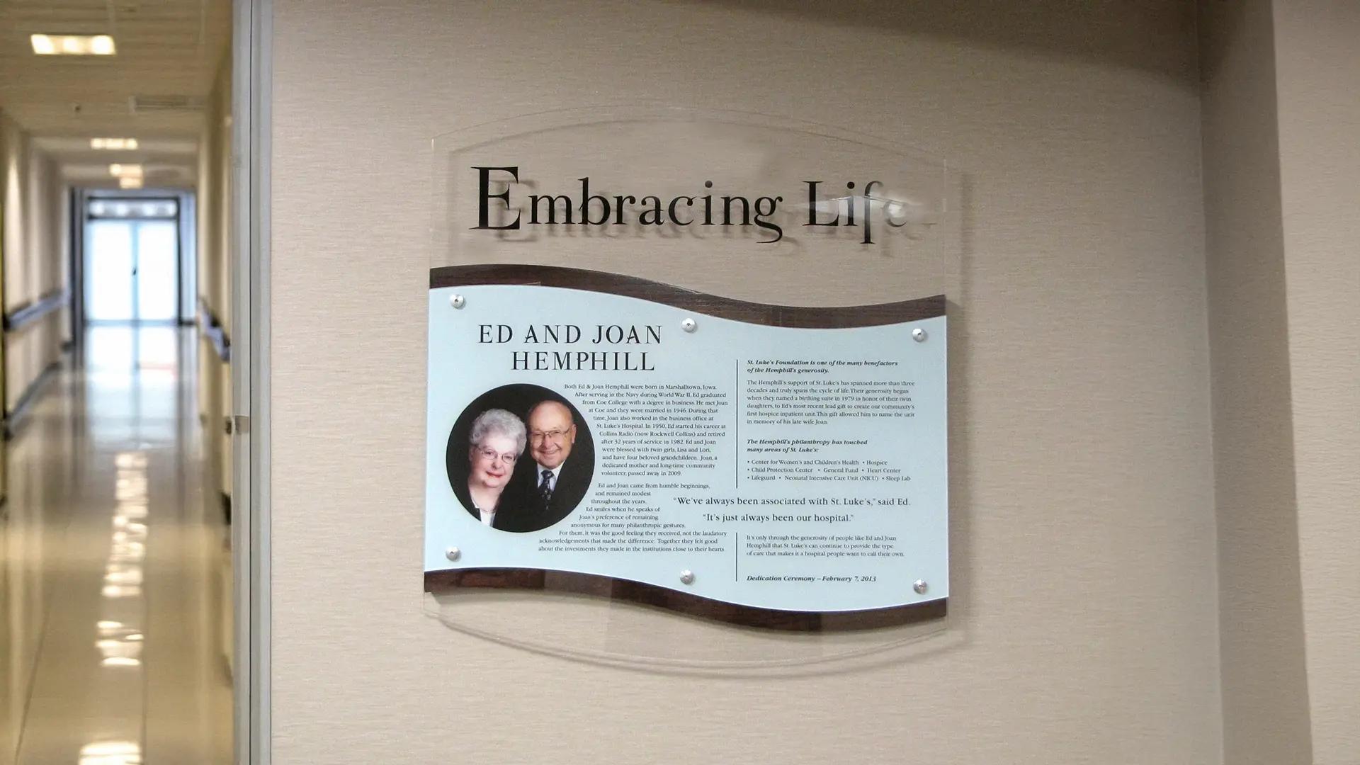 Hospice donor plaque honoring Ed and Joan Hemphill at UnityPoint Hospice, featuring layered acrylic and wood accents in a quiet hallway setting.