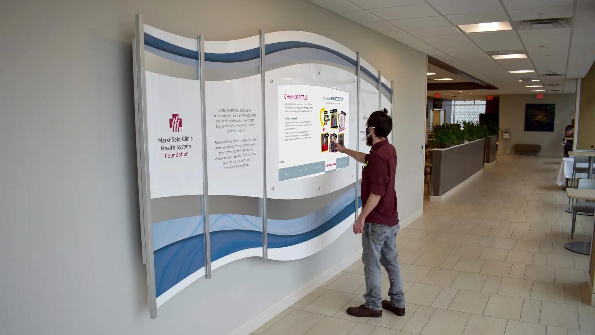 Interactive healthcare digital donor wall with curved panels and an Arreya-powered touchscreen for exploring donor stories and impact.