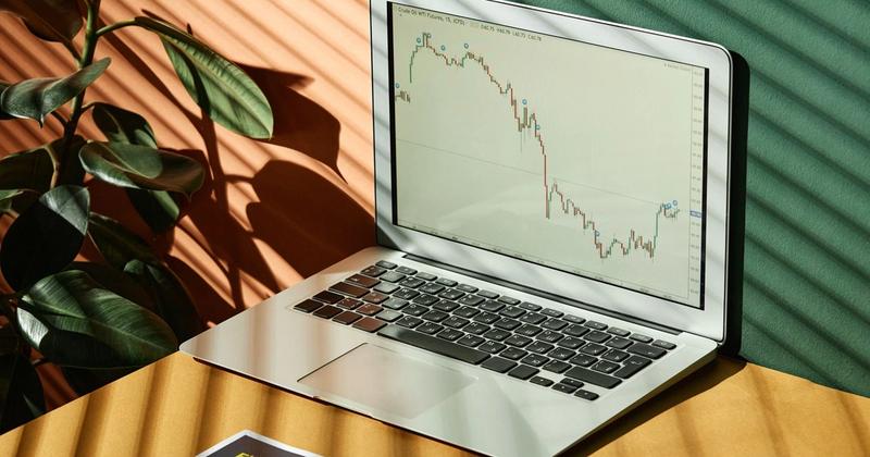 Laptop showing a financial chart on a sunlit desk, representing no-code automated stock trading in 2026