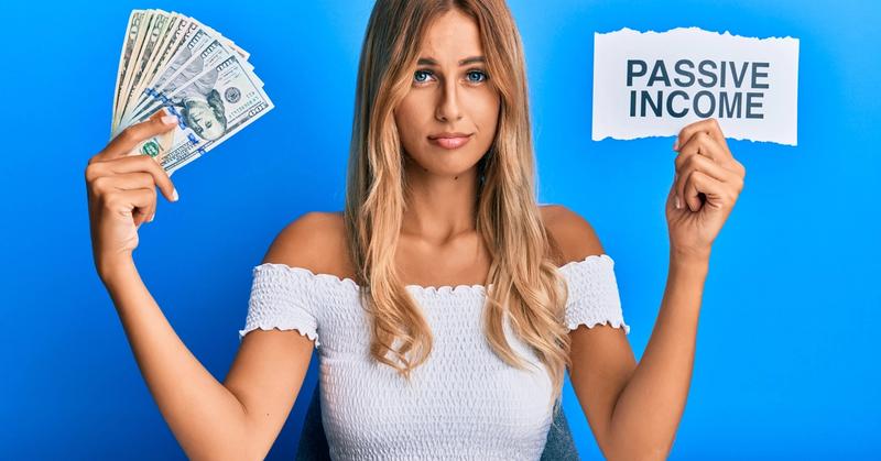 Woman holding a fan of US dollar bills and a paper sign reading Passive Income against a blue background