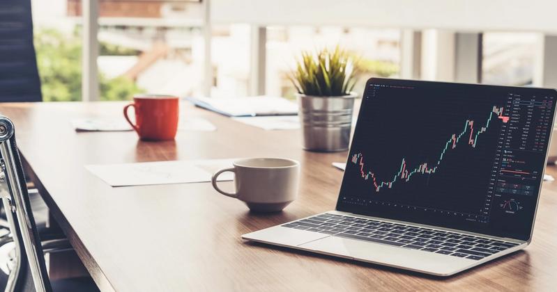 Laptop on a desk displaying a stock chart, representing AI trading apps compared in 2026