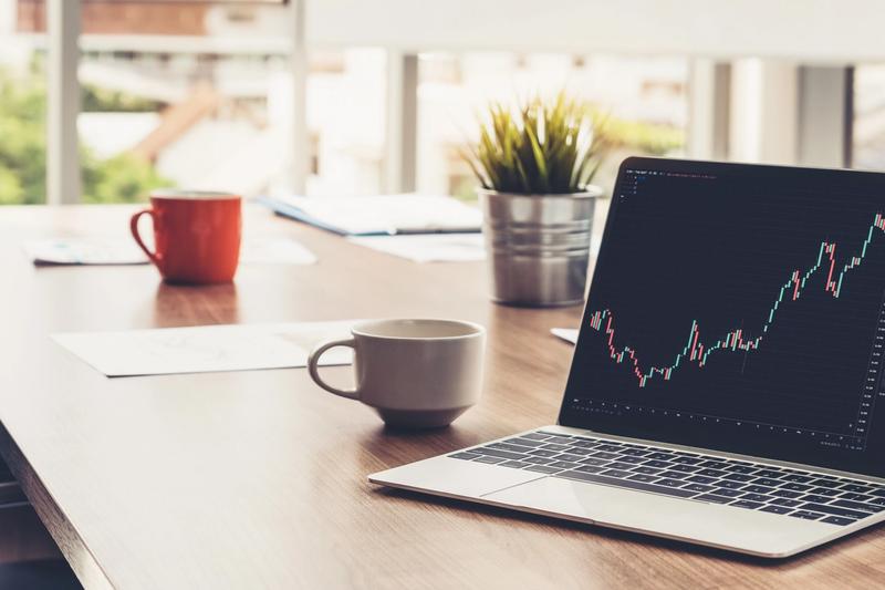 Laptop on a desk displaying a stock chart, representing AI trading apps compared in 2026