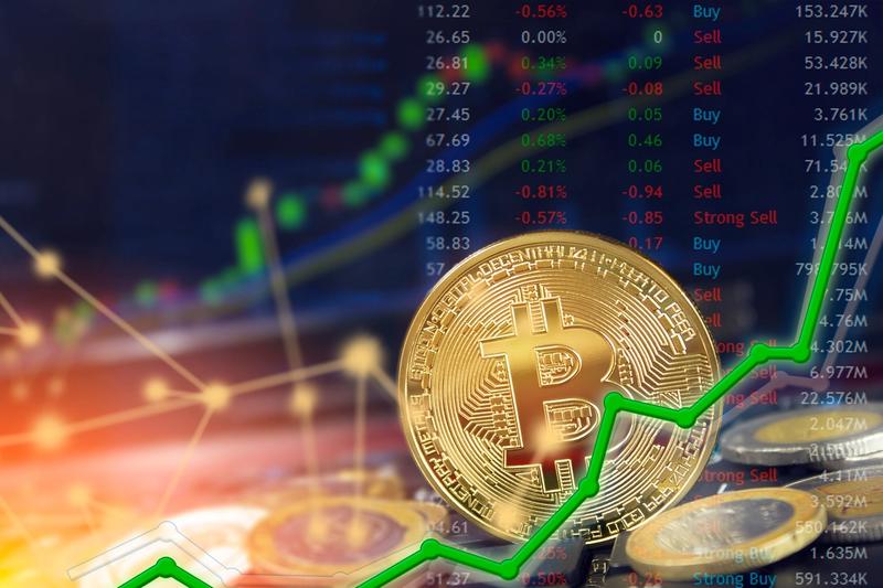 Gold bitcoin coin among other coins in front of a price board with buy and sell ratings and a green line chart