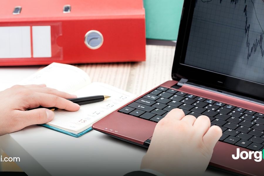 Hands at a laptop showing a stock chart beside a planner, cover for the turn-of-the-month effect study