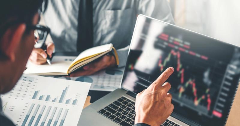 man pointing to laptop looking at financial chart
