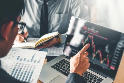man pointing to laptop looking at financial chart
