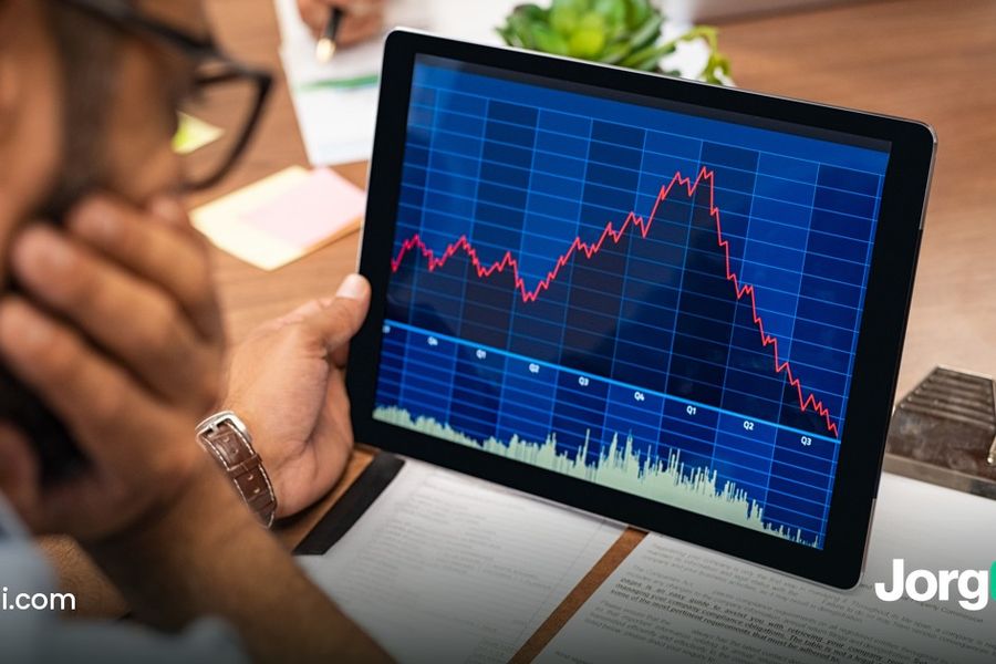 Trader reviewing a falling stock chart on a tablet at a desk