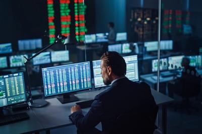 Trader reviewing multiple market data screens in a dark trading room, representing a hands-on Tradier brokerage review