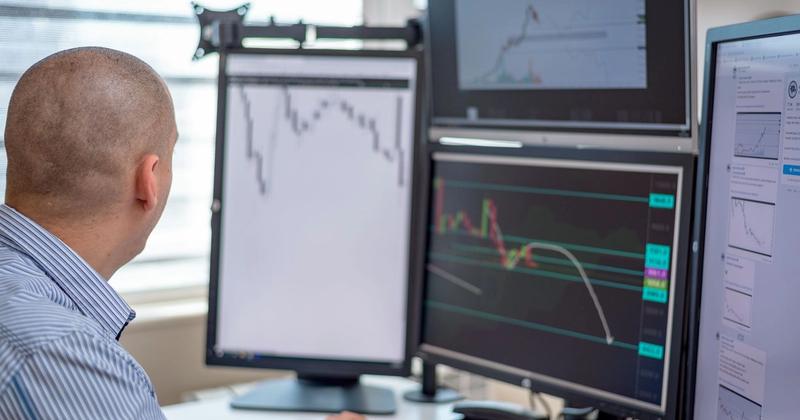 Trader reviewing charts across multiple monitors, representing automated trading on thinkorswim
