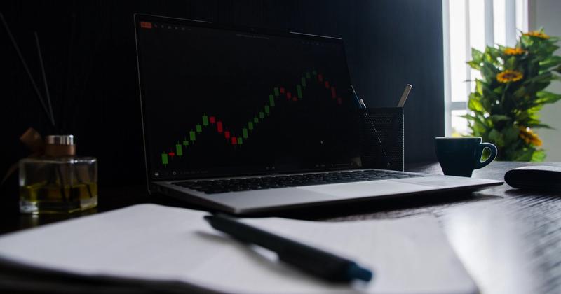 Trading desk with a laptop chart and a notebook for journaling trades