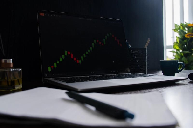 Trading desk with a laptop chart and a notebook for journaling trades