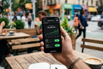Investor checking a mobile trading app on a phone at a cafe