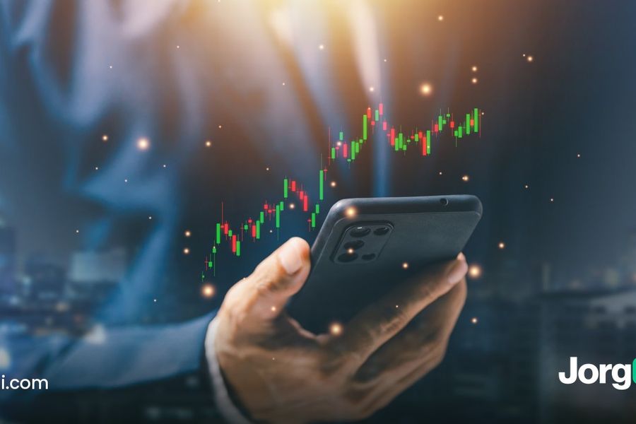 Hand holding a phone with a stock chart against a city skyline at night, cover for the September 2026 retail sales preview