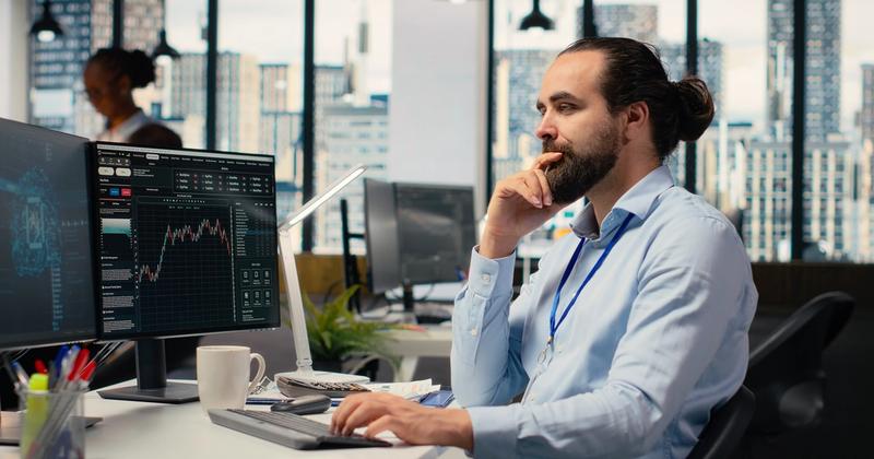 Trader at a multi-monitor desk setting up automated trading, representing no-code Alpaca account automation
