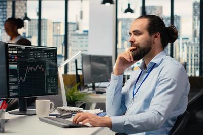 Trader at a multi-monitor desk setting up automated trading, representing no-code Alpaca account automation
