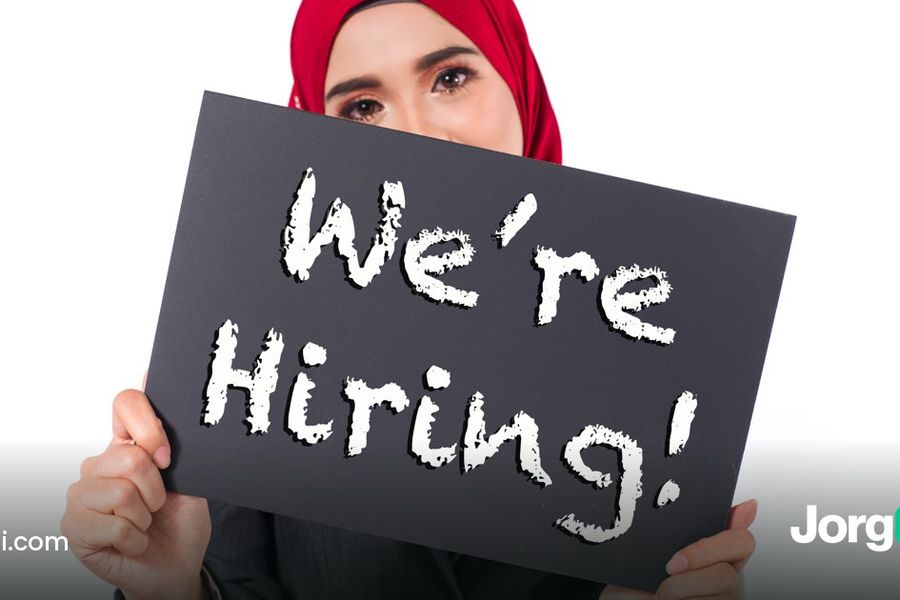 Businesswoman holding a We're Hiring sign in an office
