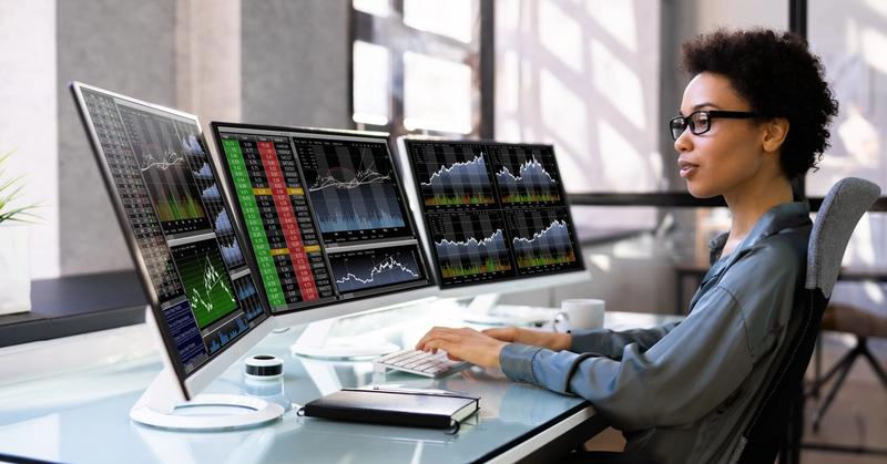 Trader at a multi-monitor desk running automated trading software connected to a brokerage API