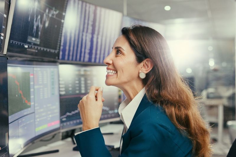 Trader smiling at a wall of stock charts, illustrating the Q3 2026 earnings season