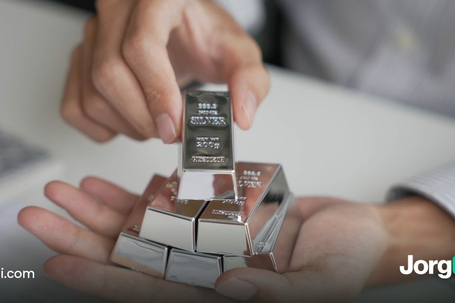 Hands holding small precious-metal bars over a desk, cover for the gold bear market post