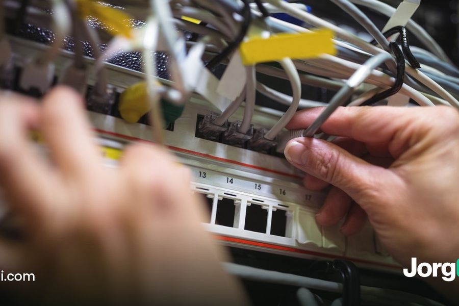 Technician plugging a patch cable into a rack-mounted server, cover for the guide to what happens to stop-losses when a broker connection drops