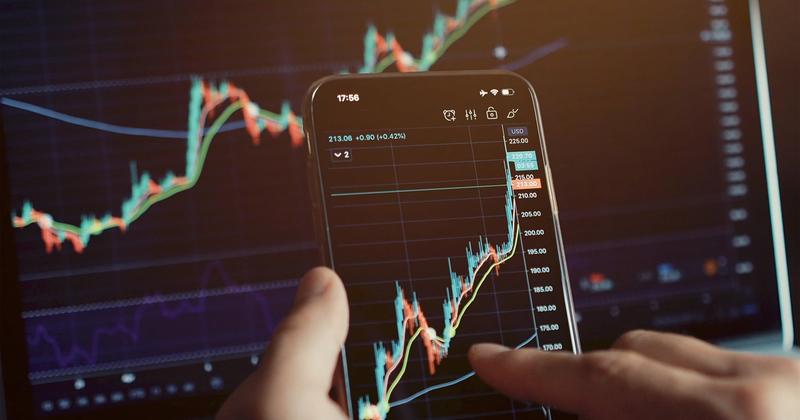 Hands using a phone to connect a brokerage account to trading charts