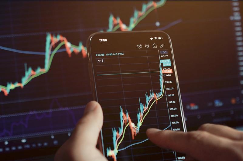 Hands using a phone to connect a brokerage account to trading charts