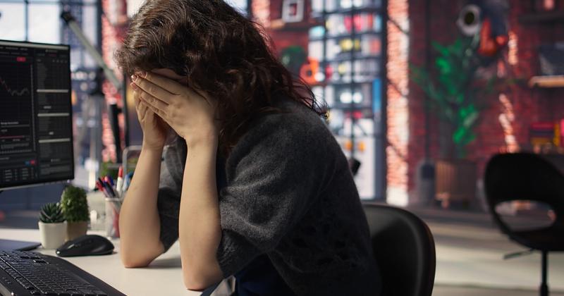 Frustrated trader at a desk of red charts after a losing session