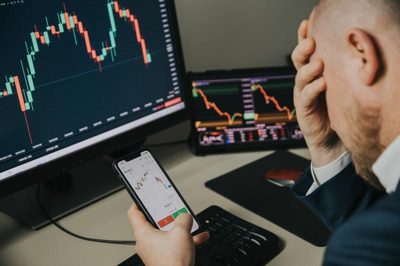 Trader at a multi-monitor desk reacting to falling stock charts after surprising economic news