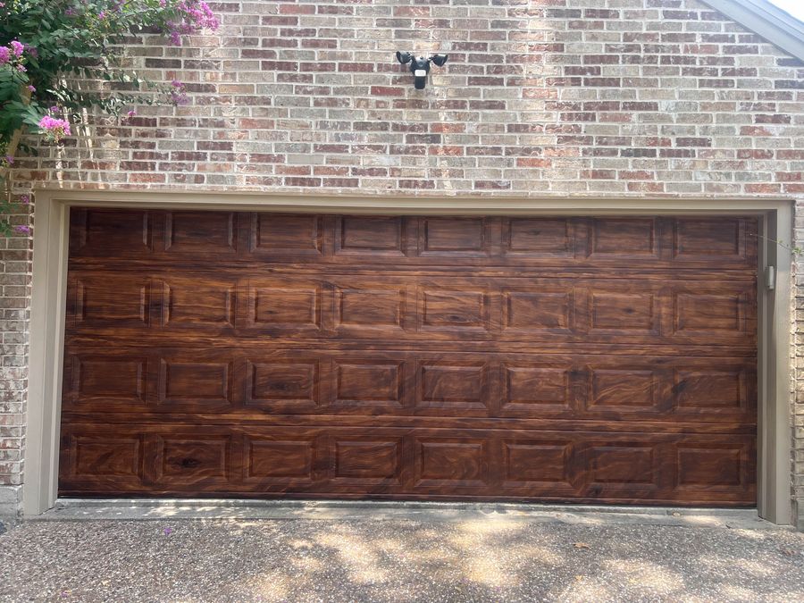 Faux-bois walnut finish on metal garage door exterior — hand-painted wood grain with knot detail, Houston residential