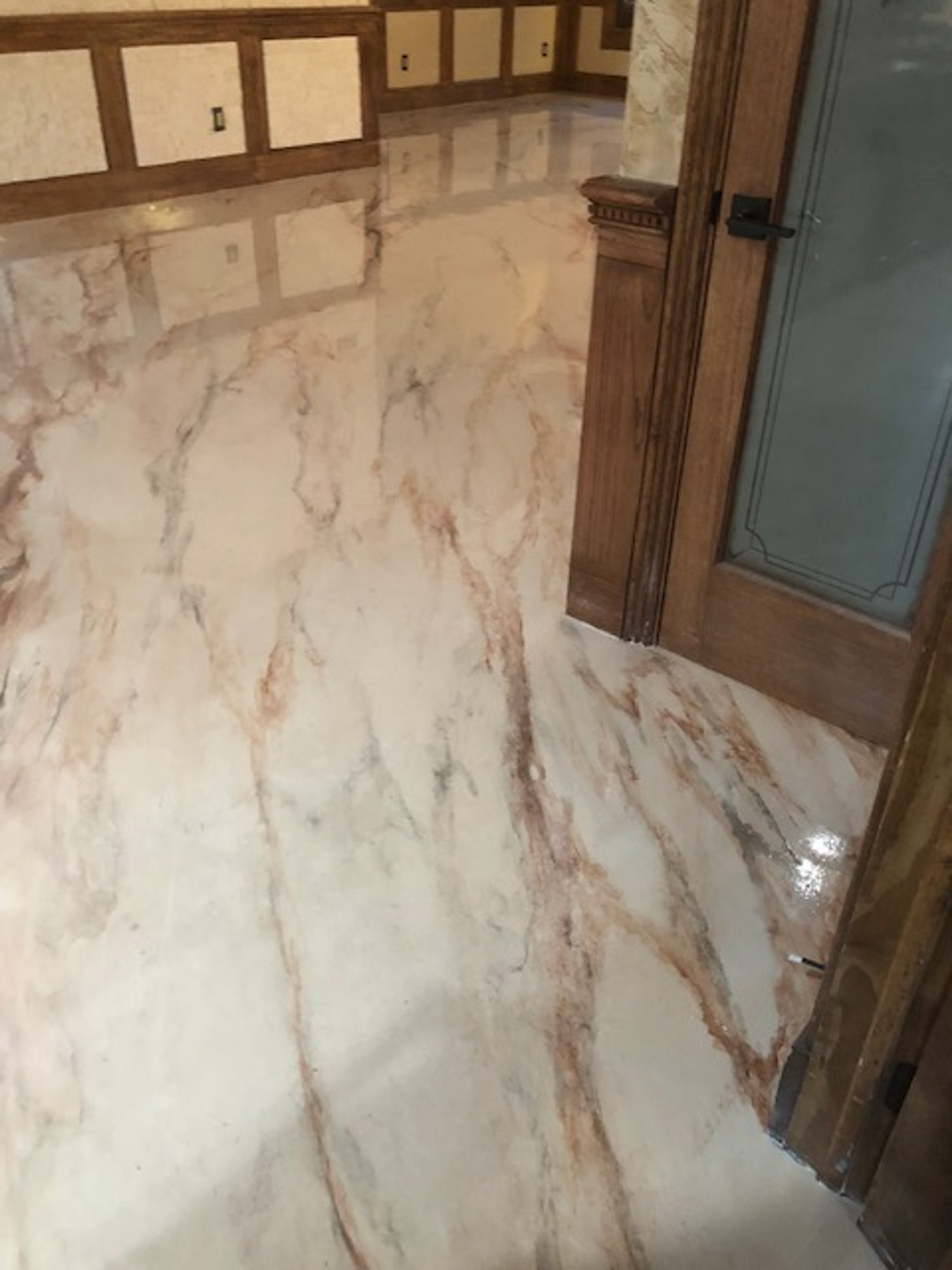 Metallic epoxy marble-effect floor in residential foyer with rust and cream veining and high-gloss reflective finish.