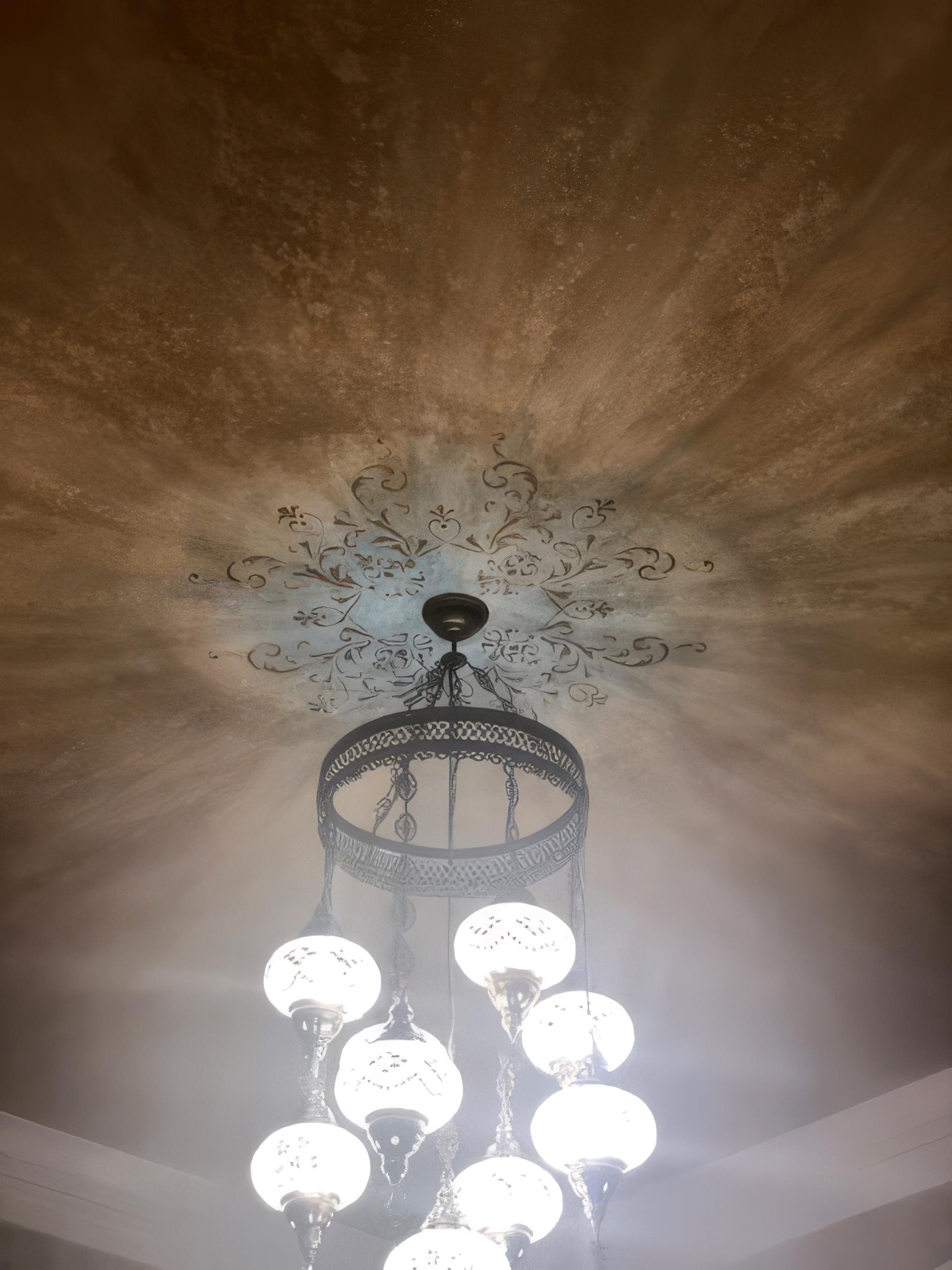 Venetian plaster ceiling with radial burnished glaze and hand-painted scroll medallion surrounding chandelier, dining room