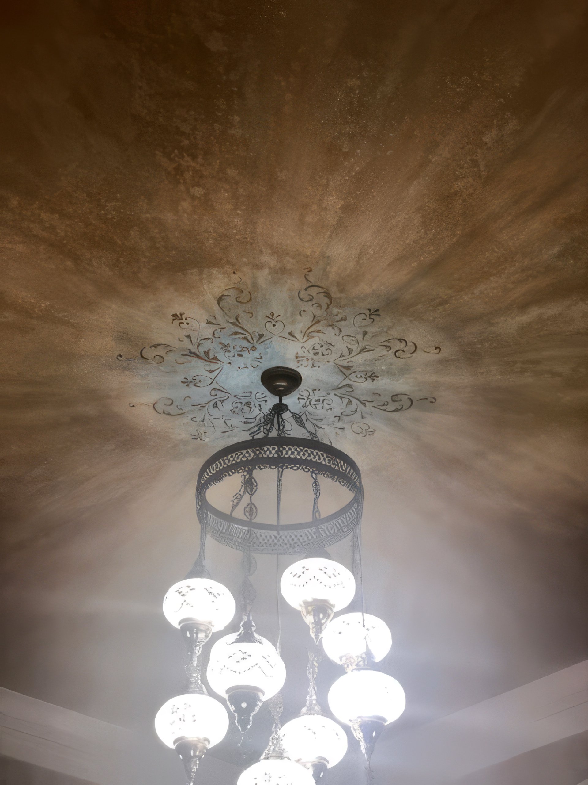 Venetian plaster ceiling with radial burnished glaze and hand-painted scroll medallion surrounding chandelier, dining room