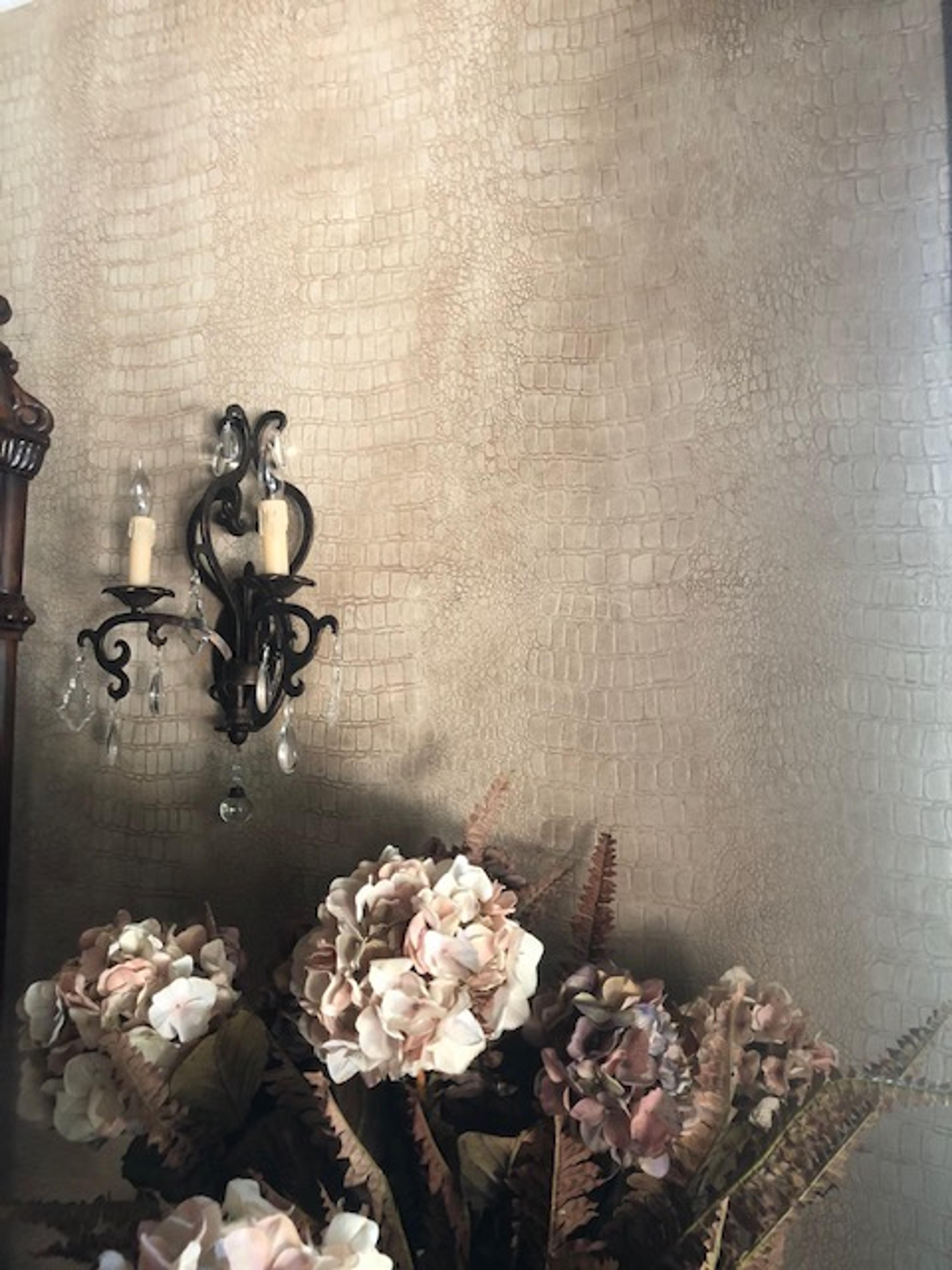 Faux crocodile leather wall finish in champagne and bronze tones, powder room, with ornate iron wall sconce.