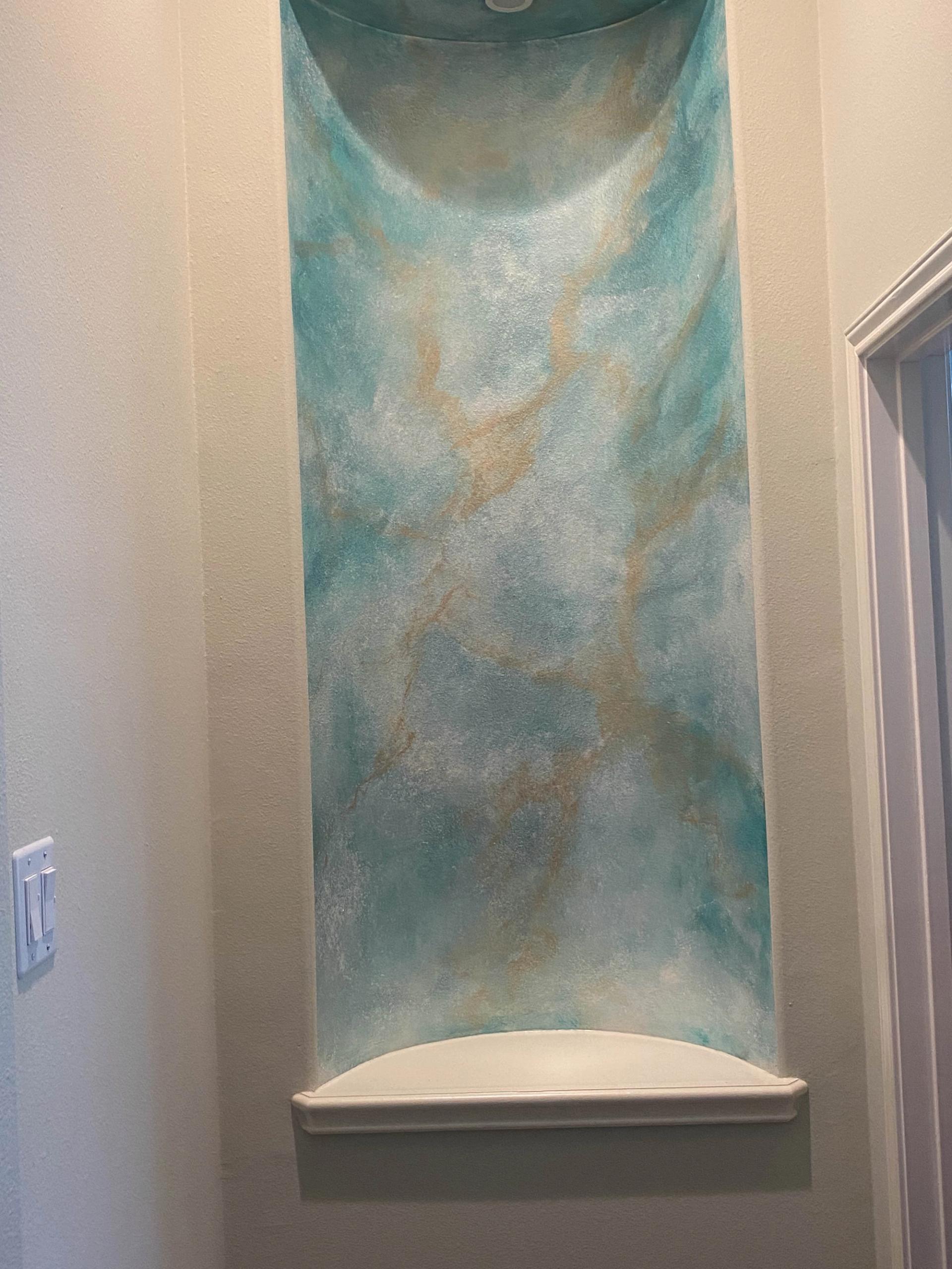 Multi-tonal turquoise Venetian plaster with gold veining inside an arched wall niche, hallway architectural detail