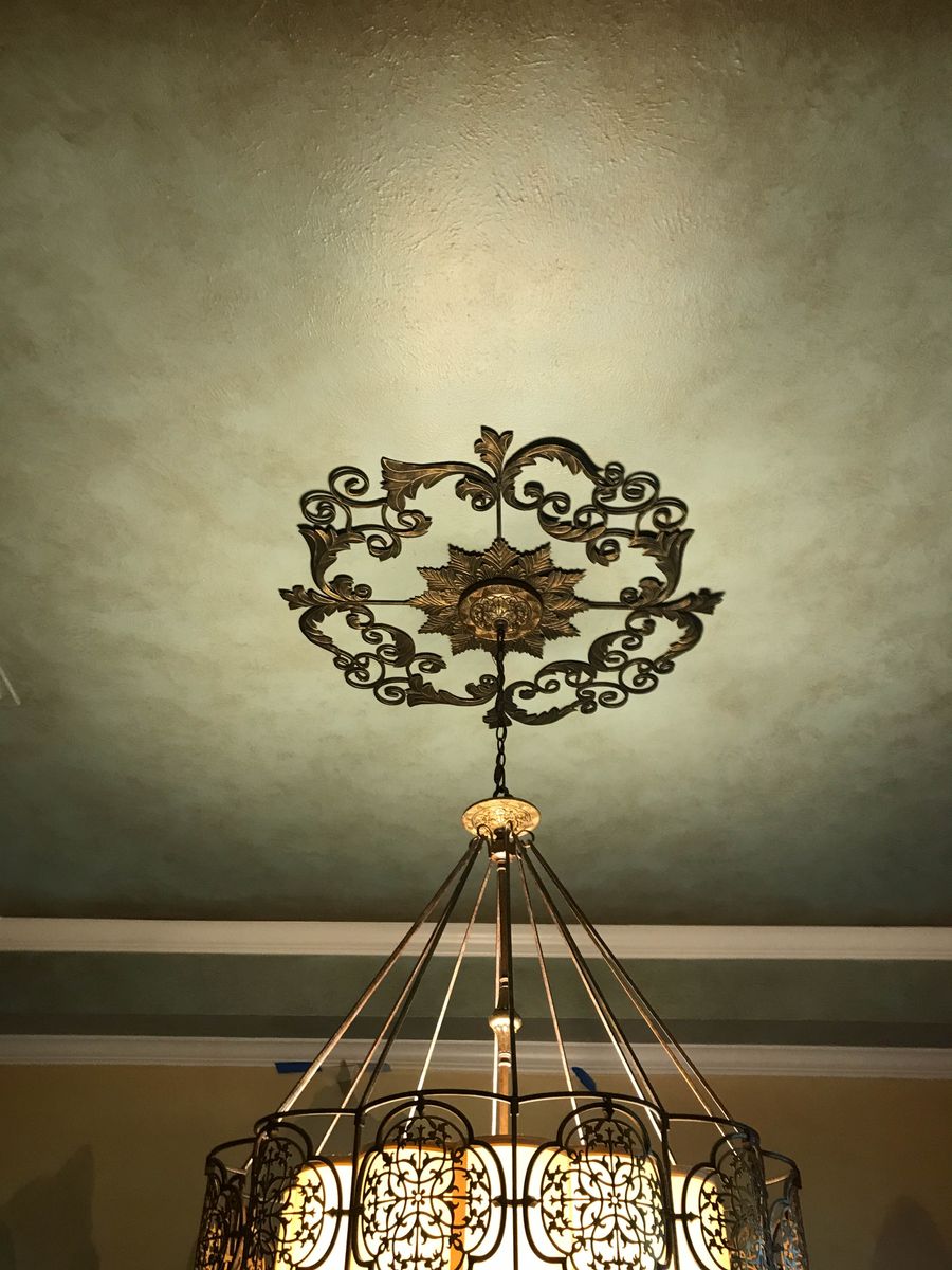 Sage olive Venetian plaster tray ceiling with ornate iron scrollwork medallion and cage chandelier, dining room.