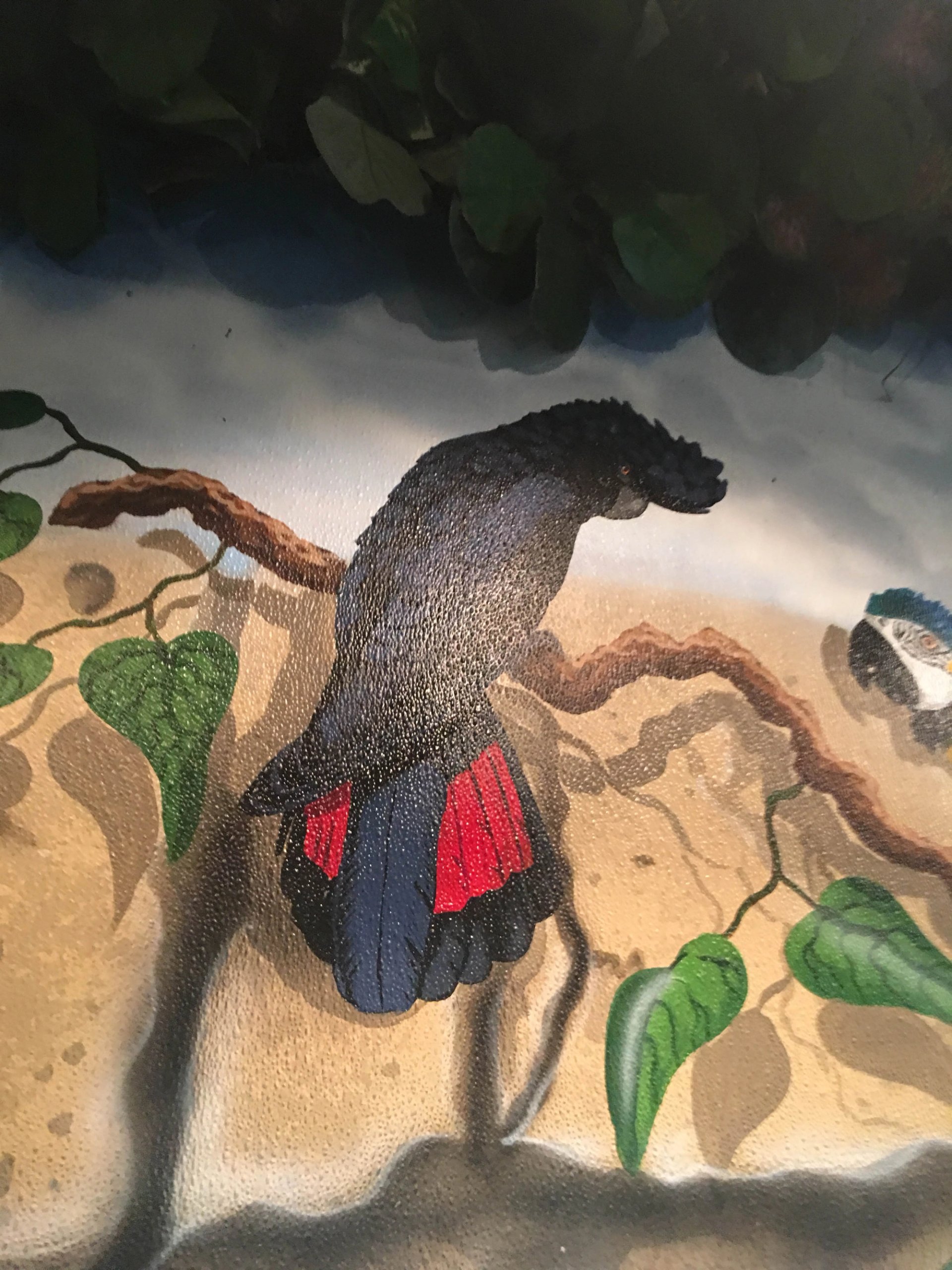 Hand-painted jungle mural detail, black cockatoo with red tail feathers on textured plaster wall, tropical wildlife theme