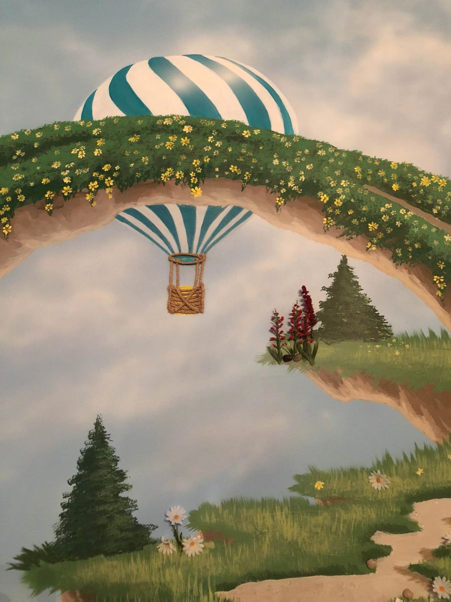 Hand-painted children's fantasy mural with teal hot air balloon passing through flower-covered stone arch bridge.