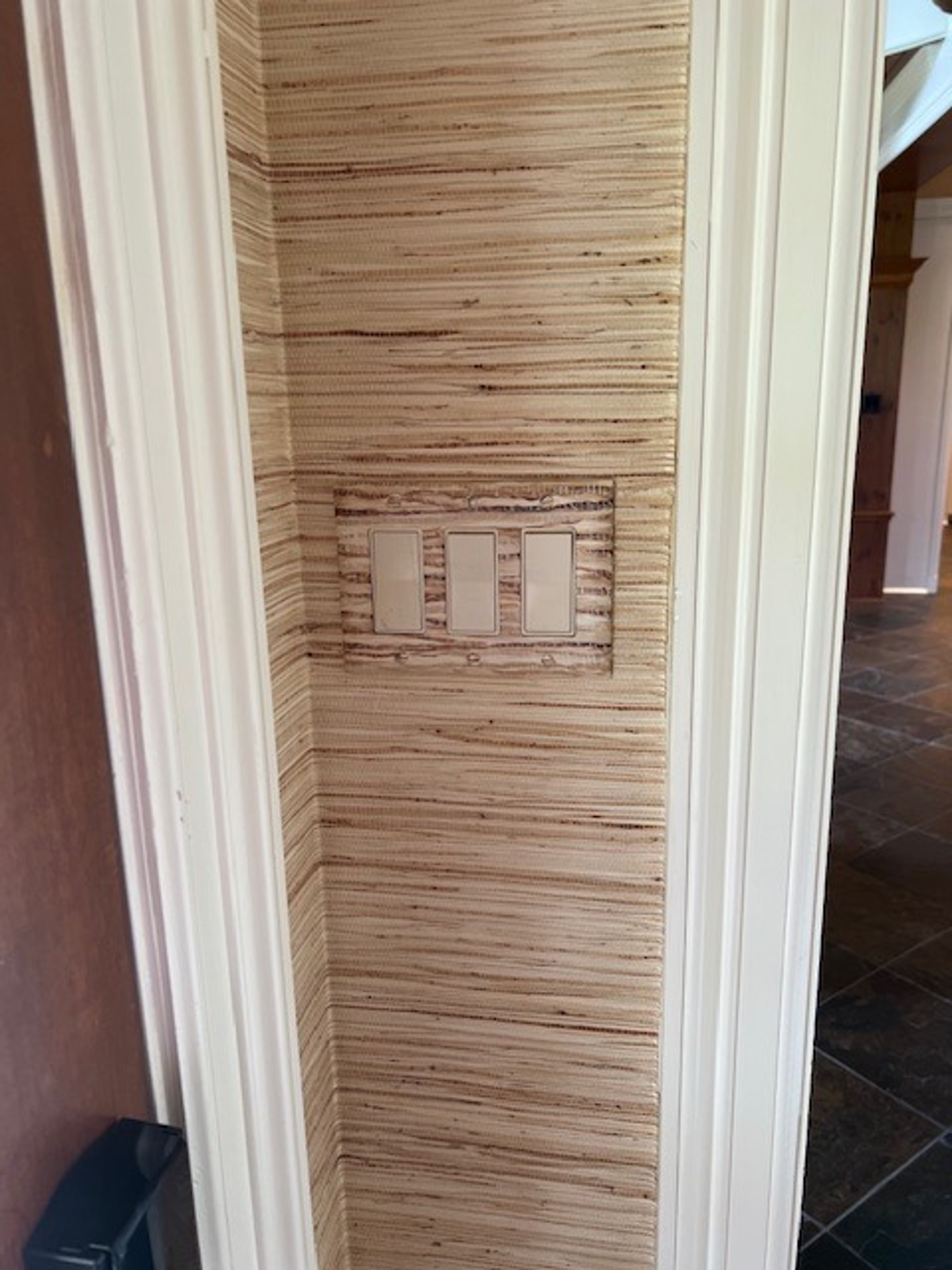 Grasscloth faux finish in warm straw tones in residential hallway with integrated double light switch plate, Houston.