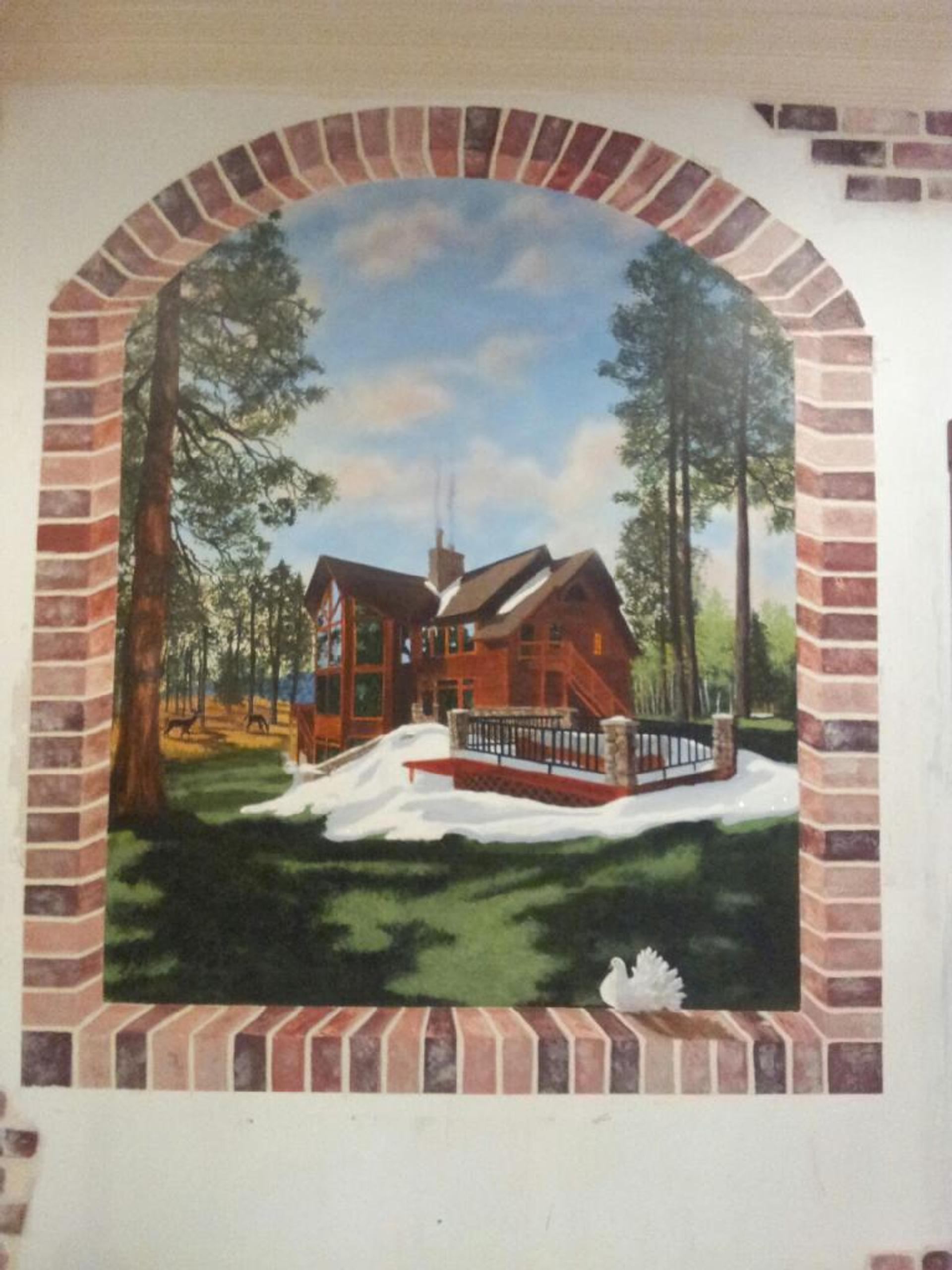 Trompe l'oeil wall mural with faux brick arch framing hand-painted log cabin in pine forest with snow