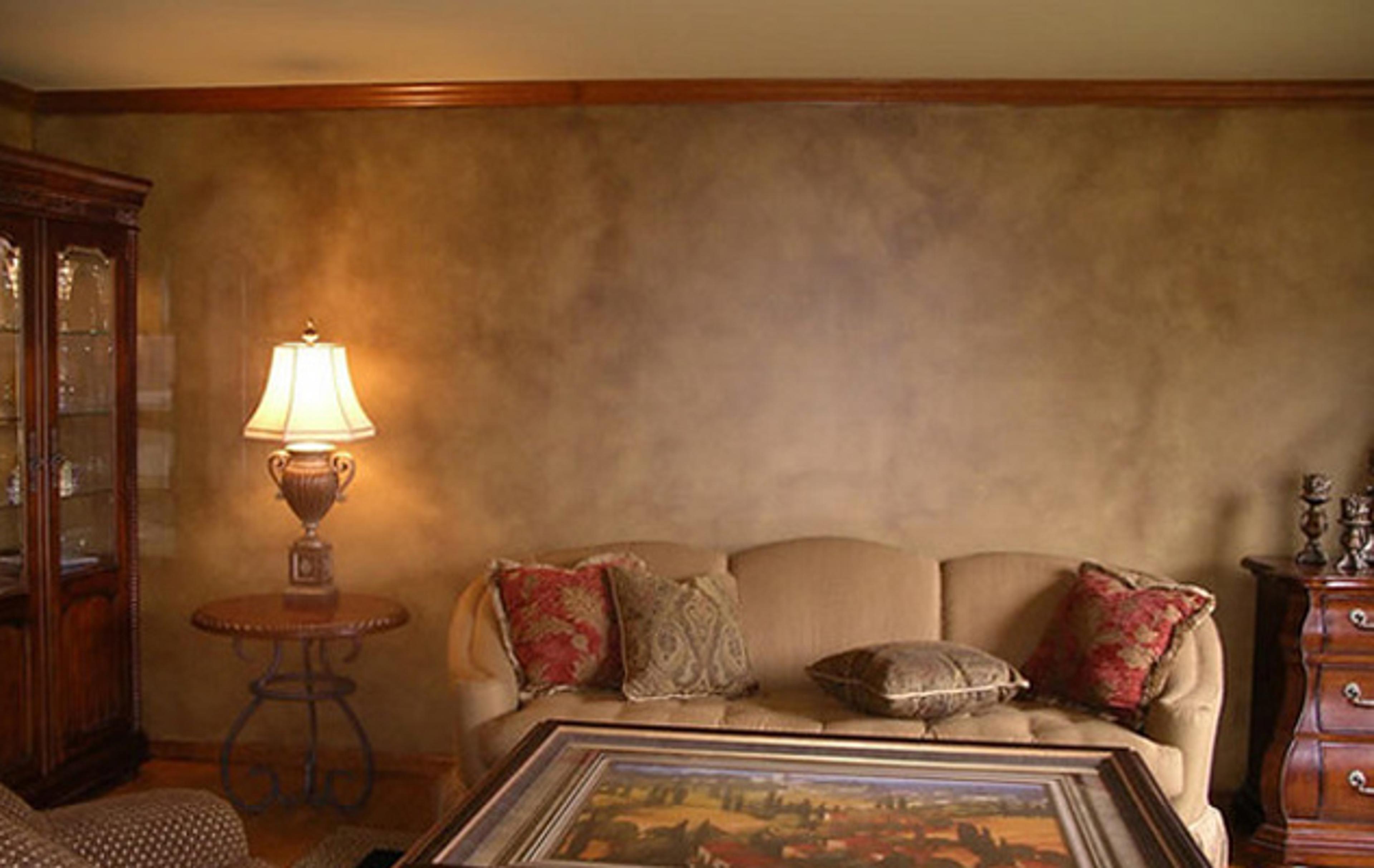 Burnished Venetian plaster in warm taupe living room with layered tonal depth behind upholstered sofa, Houston TX