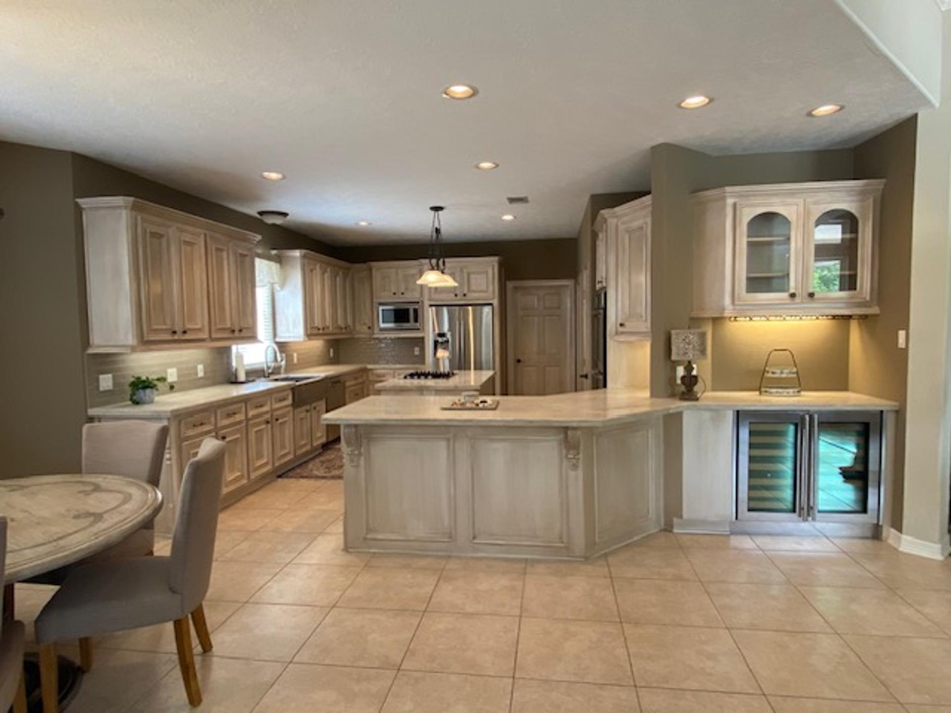 Antiqued glaze faux finish on raised-panel kitchen cabinets and island with carved corbels, Houston residential kitchen.