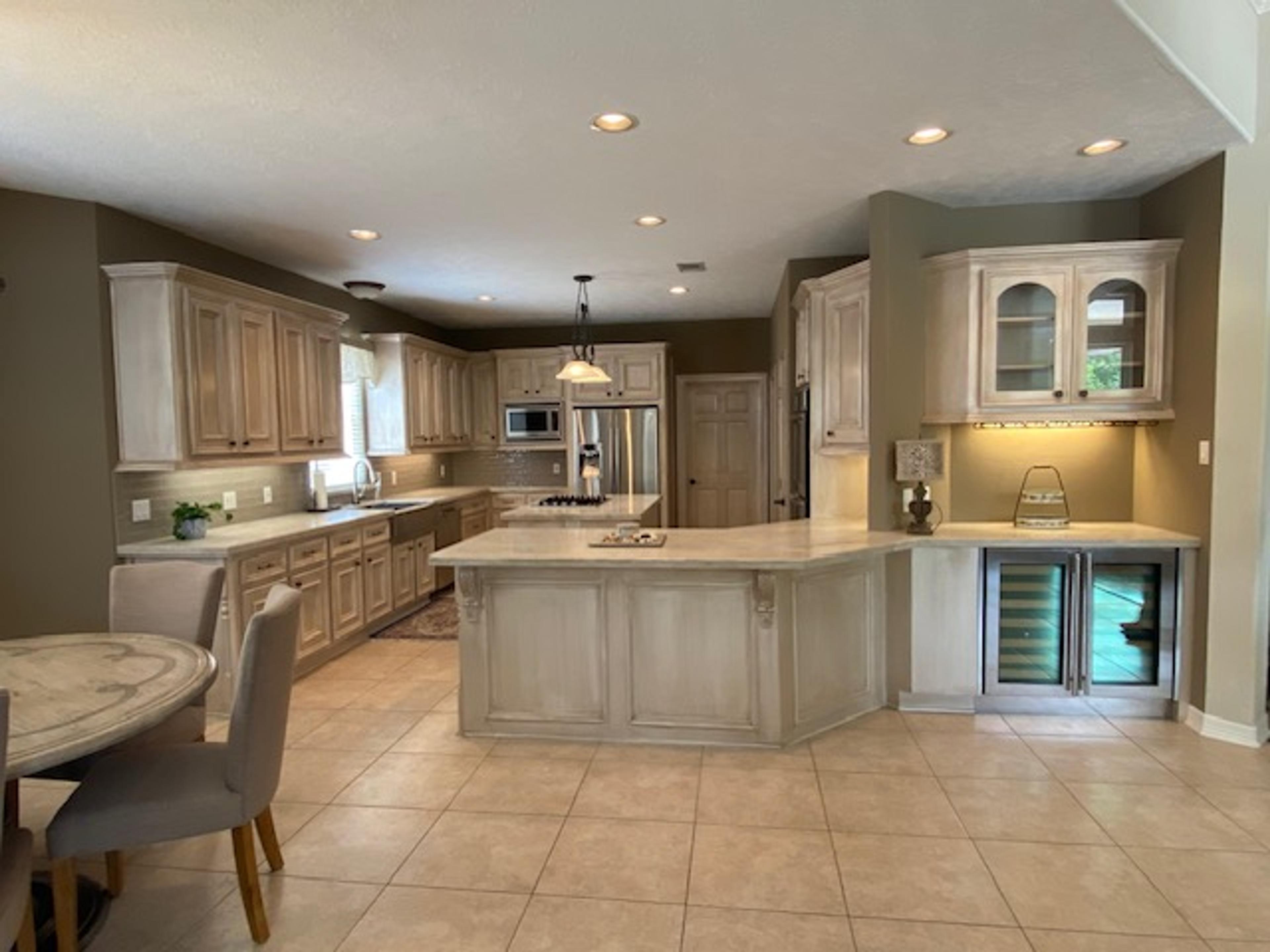 Antiqued glaze faux finish on raised-panel kitchen cabinets and island with carved corbels, Houston residential kitchen.