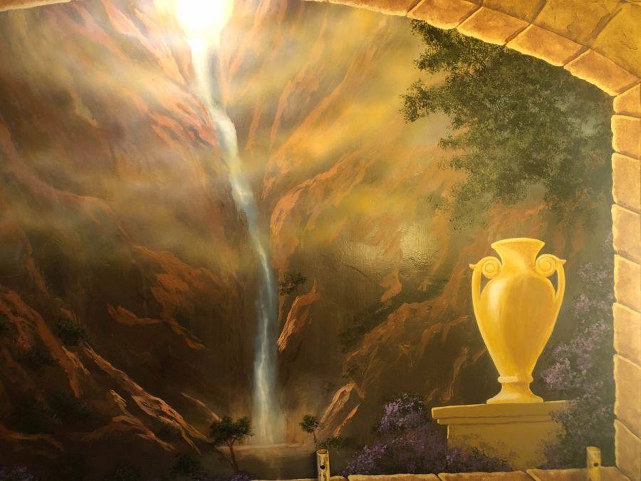 Trompe l'oeil mural with cascading waterfall, golden light rays, classical Greek urn on stone pedestal, and rocky gorge
