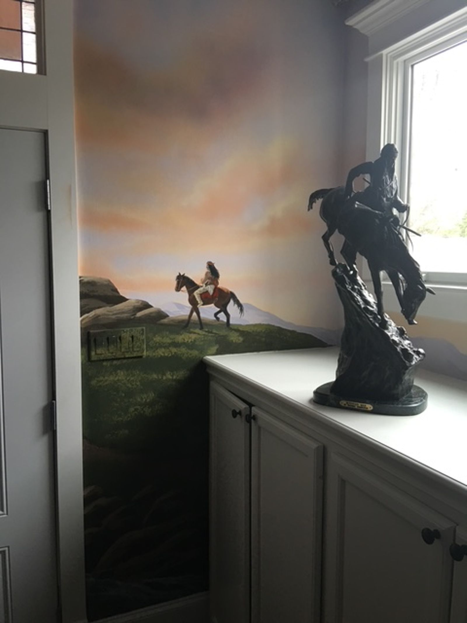 Hand-painted Early American frontier mural in law firm corner with horseback rider and warm sunset sky, Houston TX