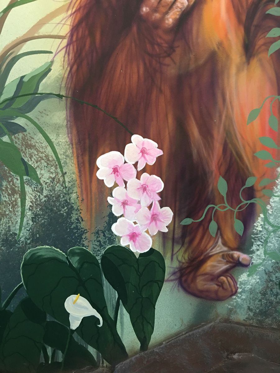 Hand-painted jungle mural detail with realistic orangutan fur, pink orchids, and calla lily on decorative wall surface.