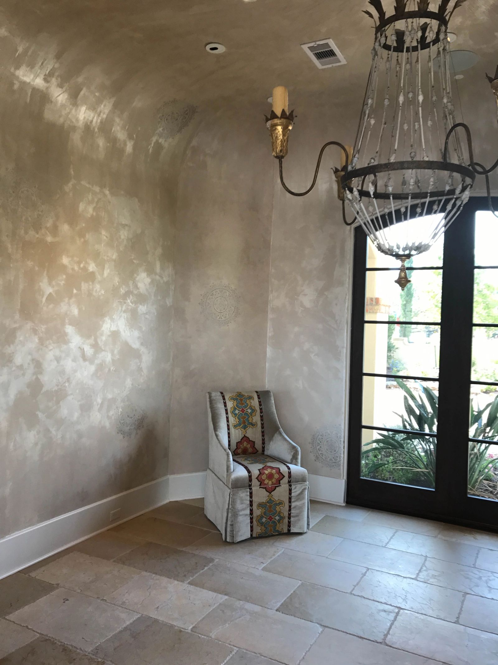 Pearlescent Venetian plaster foyer walls with tone-on-tone stencil medallions, warm cream and gold metallic finish, Houston luxury home.