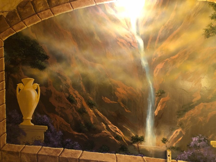 Trompe l'oeil wall mural with stone arch, waterfall gorge, Greek urn, and golden atmospheric light — Houston decorative art