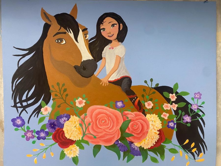 Hand-painted cartoon character mural in children's bedroom, girl on horse with floral foreground on periwinkle blue wall