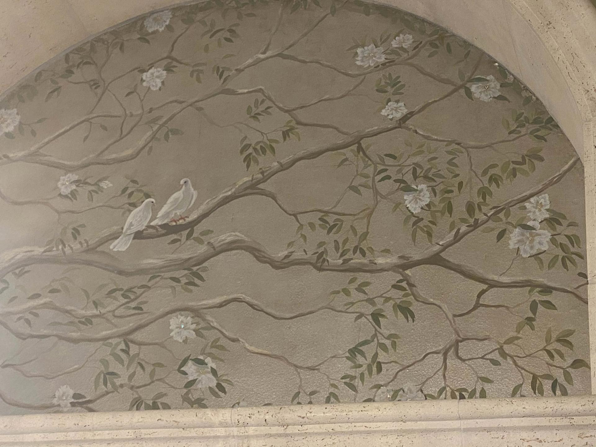 Hand-painted chinoiserie mural in arched niche with white doves, blossoms, and sage-green plaster ground