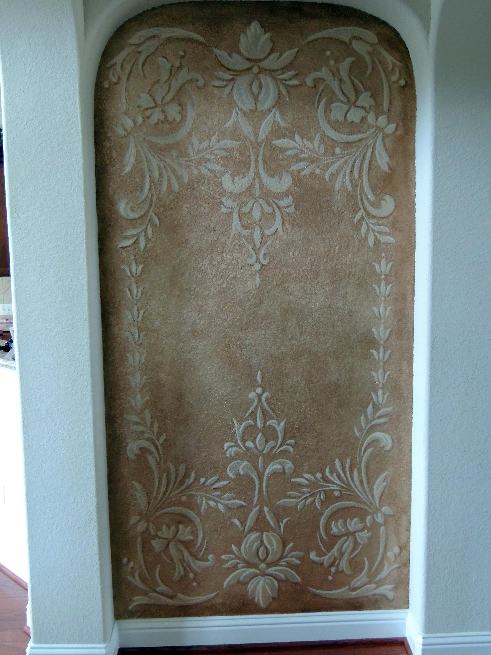 Venetian plaster arched niche with tone-on-tone damask stencil in warm amber and cream, residential foyer.